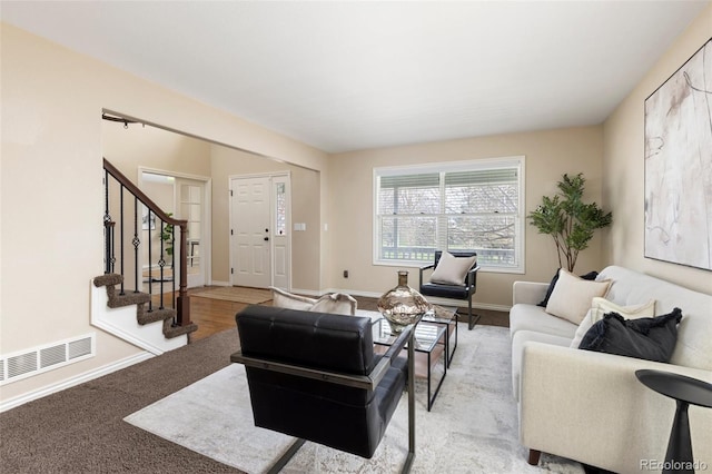 living room with stairs, baseboards, visible vents, and light carpet