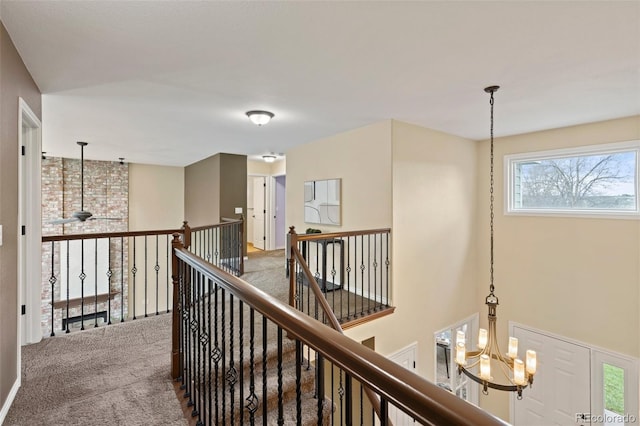 corridor featuring carpet floors, an upstairs landing, and an inviting chandelier