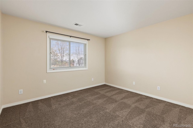 spare room with baseboards, dark colored carpet, and visible vents