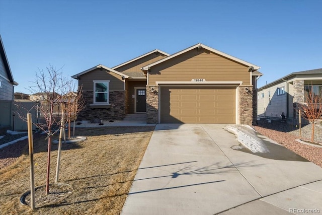 view of front of property with an attached garage, stone siding, and concrete driveway