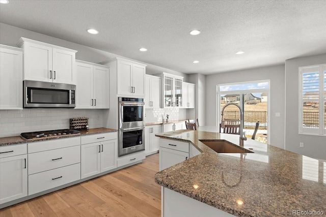 kitchen featuring appliances with stainless steel finishes, light wood-type flooring, a sink, and white cabinetry