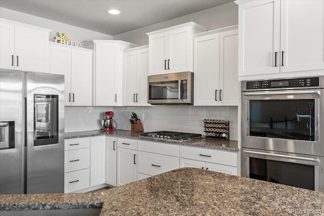 kitchen with appliances with stainless steel finishes, dark stone counters, and decorative backsplash