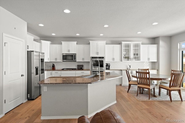 kitchen with light wood-style floors, appliances with stainless steel finishes, white cabinets, and a sink