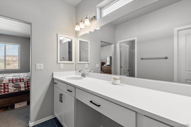 ensuite bathroom with a textured wall, ensuite bath, baseboards, and vanity