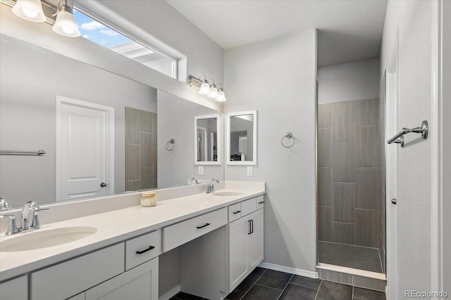 bathroom with double vanity, walk in shower, a sink, and tile patterned floors