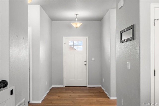 entryway featuring visible vents, baseboards, and wood finished floors