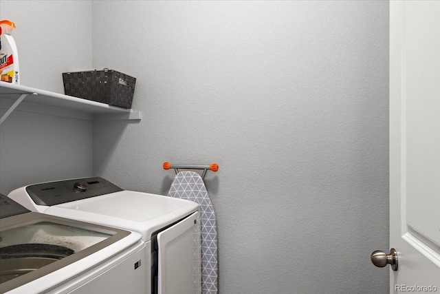 clothes washing area featuring a textured wall, laundry area, and independent washer and dryer