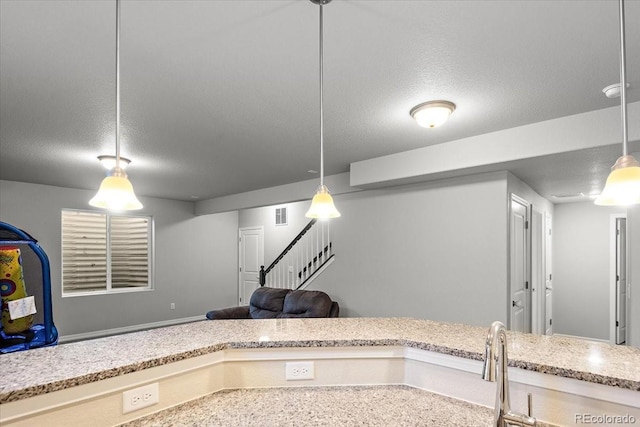 kitchen featuring light stone countertops, visible vents, pendant lighting, and a textured ceiling