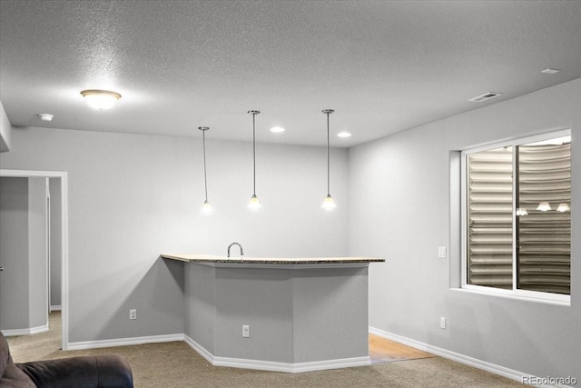 kitchen with baseboards, visible vents, a textured ceiling, and light colored carpet