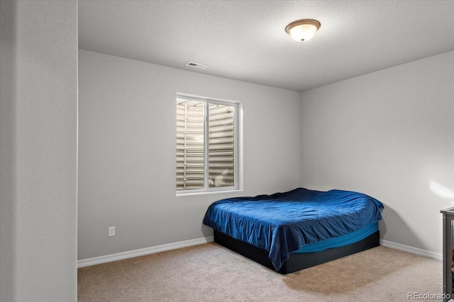 bedroom with carpet, a textured ceiling, visible vents, and baseboards