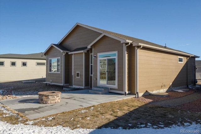 rear view of property featuring entry steps, an outdoor fire pit, and a patio