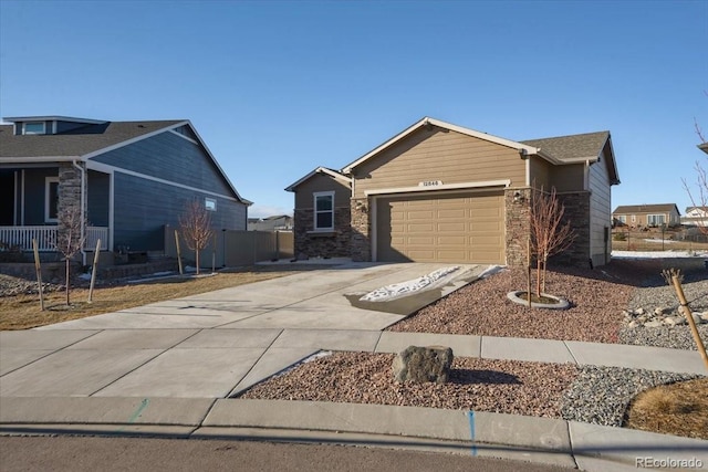 single story home featuring a garage, concrete driveway, stone siding, and fence