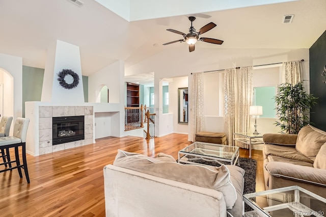 living room featuring ceiling fan, lofted ceiling, a fireplace, and light hardwood / wood-style flooring