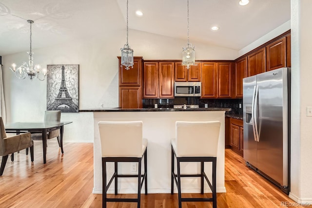 kitchen featuring stainless steel appliances, a center island, a breakfast bar, and pendant lighting