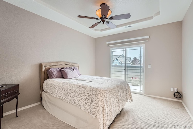 bedroom featuring ceiling fan, light colored carpet, a raised ceiling, and access to outside