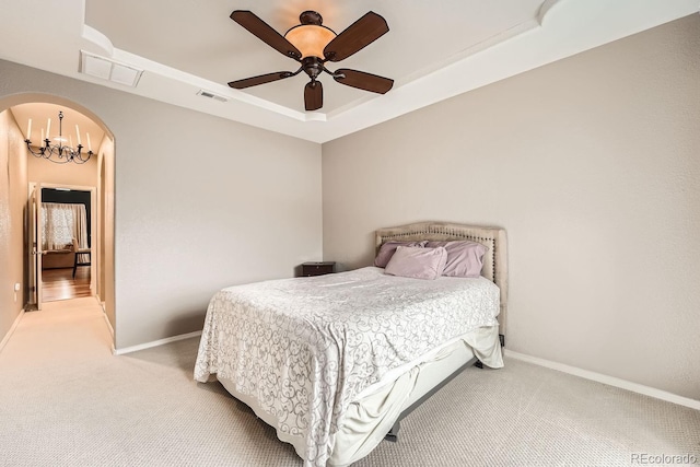 bedroom with ceiling fan with notable chandelier, light carpet, and a tray ceiling