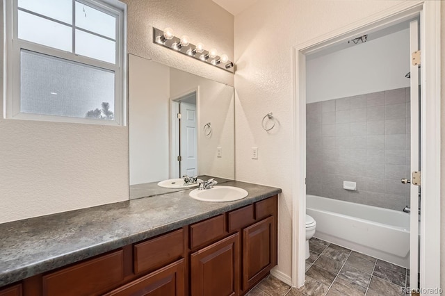 full bathroom featuring tiled shower / bath combo, vanity, and toilet