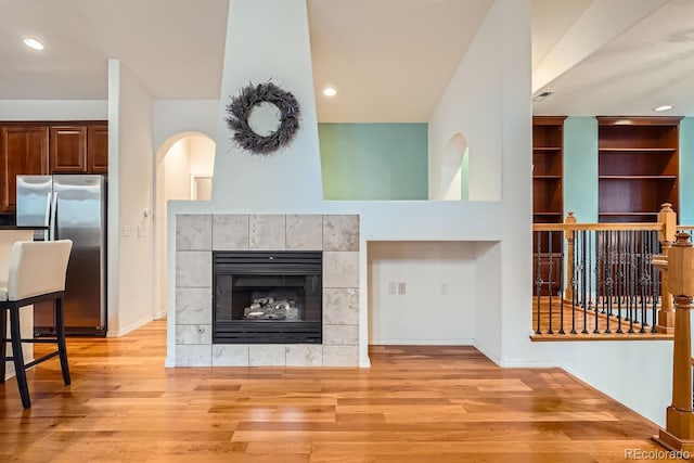 living room featuring a tiled fireplace and light hardwood / wood-style floors