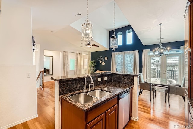 kitchen featuring sink, decorative light fixtures, light hardwood / wood-style flooring, stainless steel dishwasher, and dark stone counters