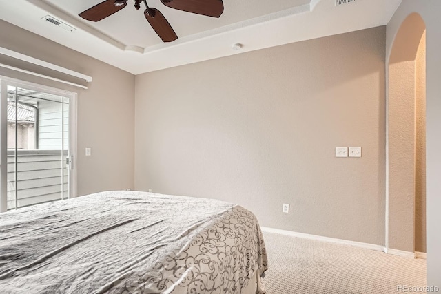 carpeted bedroom with a raised ceiling and ceiling fan