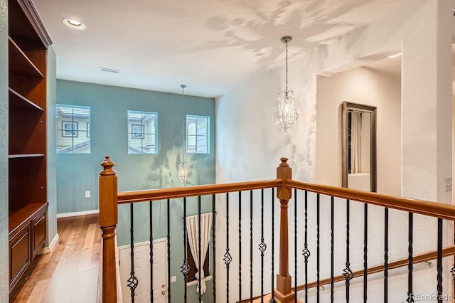 hallway featuring a notable chandelier and wood-type flooring