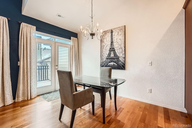 dining area featuring french doors, a chandelier, and light hardwood / wood-style flooring