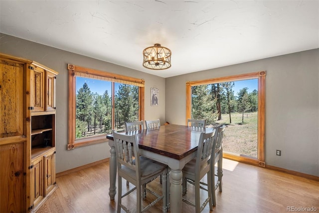 dining space with an inviting chandelier, a healthy amount of sunlight, and light wood-type flooring