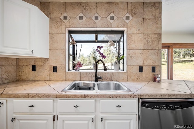 kitchen featuring tasteful backsplash, stainless steel dishwasher, sink, tile countertops, and white cabinets