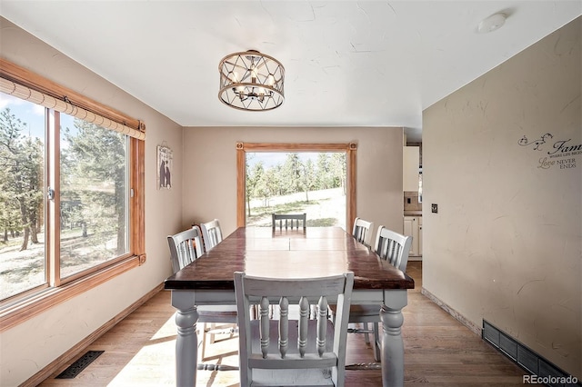 dining area featuring a healthy amount of sunlight, light hardwood / wood-style floors, and a chandelier