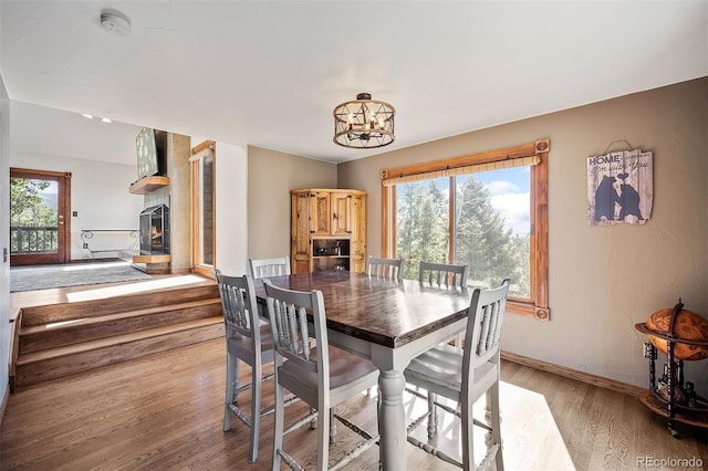 dining space with a large fireplace, a chandelier, and light wood-type flooring