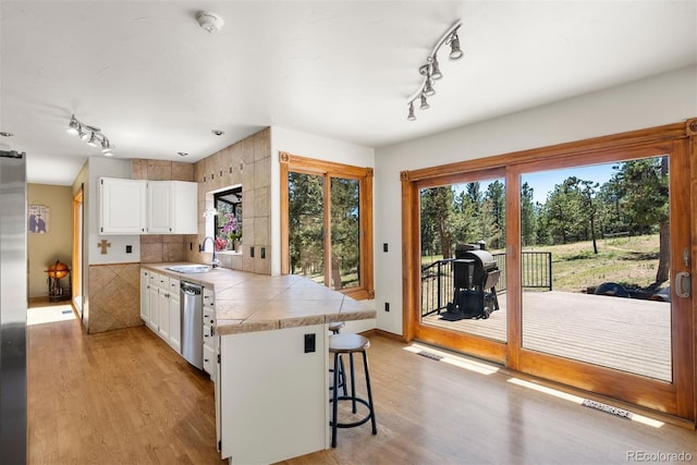 kitchen with sink, stainless steel appliances, a breakfast bar, white cabinets, and light wood-type flooring