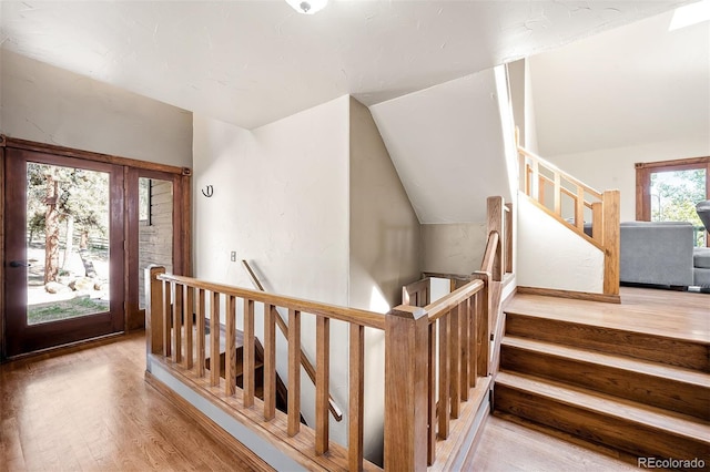 stairway with hardwood / wood-style floors and vaulted ceiling