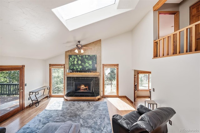 living room featuring a skylight, ceiling fan, light hardwood / wood-style flooring, and a healthy amount of sunlight