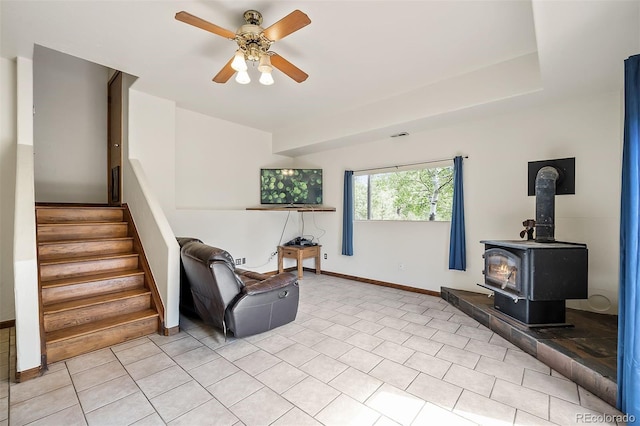 living area featuring a wood stove and ceiling fan