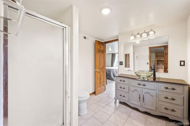 bathroom with toilet, vanity, tile patterned floors, and a shower with door