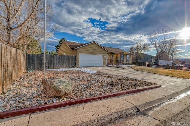 view of front of home featuring a garage, concrete driveway, and fence