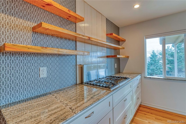 kitchen featuring open shelves, tasteful backsplash, stainless steel gas stovetop, white cabinets, and light stone countertops