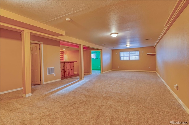 unfurnished room with carpet, visible vents, and a textured ceiling