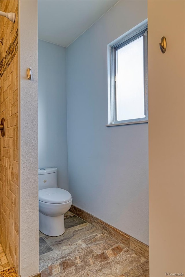 full bath with toilet and baseboards