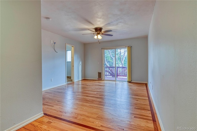 empty room featuring a ceiling fan, baseboards, a textured ceiling, and light wood finished floors