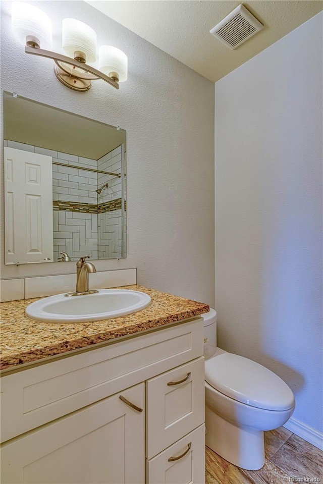 full bath with toilet, visible vents, and vanity