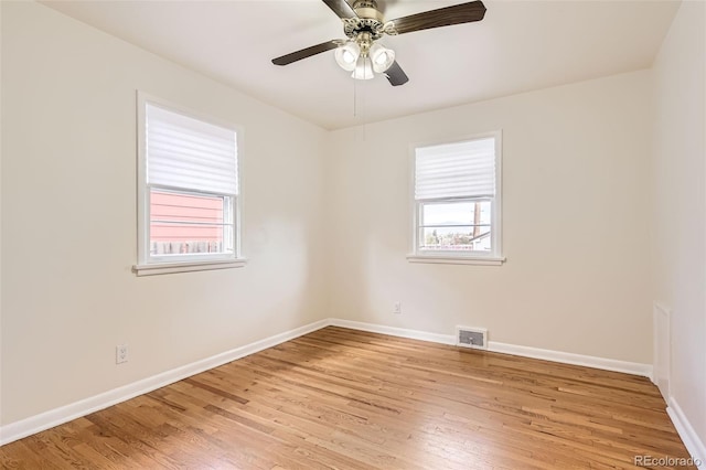 spare room featuring baseboards, light wood-style floors, visible vents, and a ceiling fan