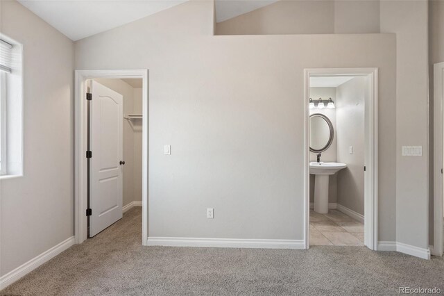 1510 York Rd Unit 100, Colorado Springs, CO 80918 - unfurnished bedroom featuring carpet flooring, a spacious closet, vaulted ceiling, baseboards, and ensuite bathroom