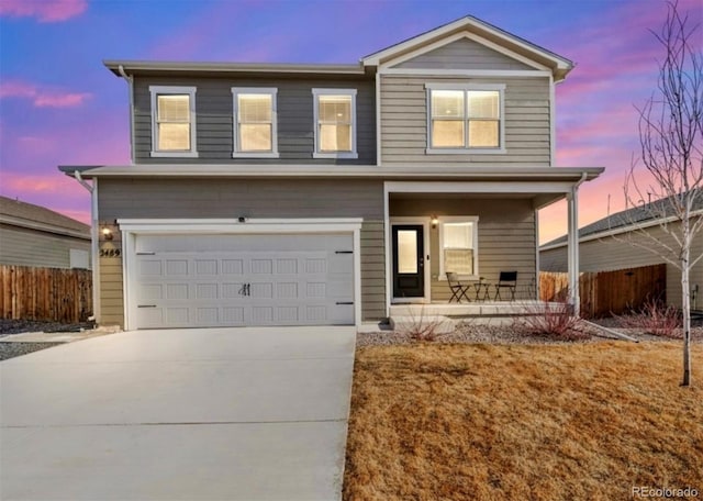 traditional-style home featuring an attached garage, covered porch, fence, and concrete driveway