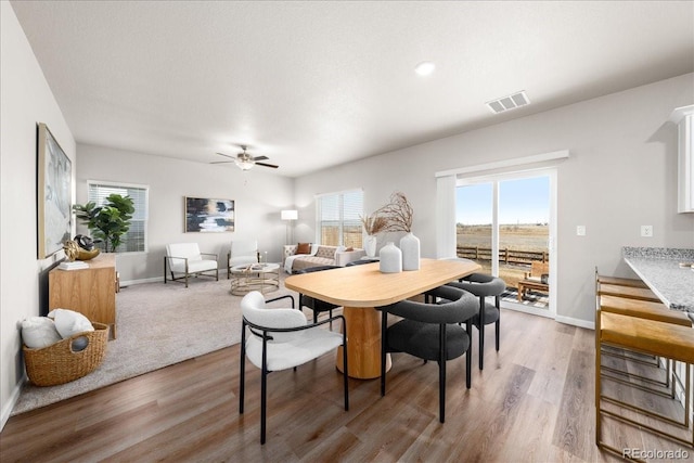 dining space featuring light wood-style flooring, visible vents, and baseboards