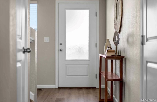 doorway featuring wood finished floors and baseboards