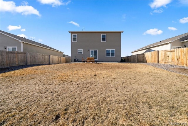 back of house with a yard and a fenced backyard