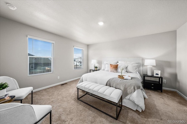 carpeted bedroom featuring visible vents, baseboards, and a textured ceiling