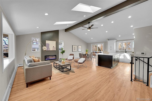 living room with lofted ceiling with beams, ceiling fan, light wood-type flooring, baseboard heating, and a large fireplace