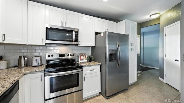 2829 Illinois Ave, Colorado Springs, CO 80907 - kitchen featuring appliances with stainless steel finishes, light tile patterned flooring, decorative backsplash, white cabinetry, and light stone countertops